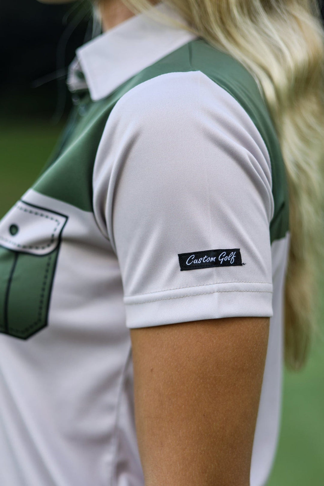 White and green golf polo shirt with pocket detail.