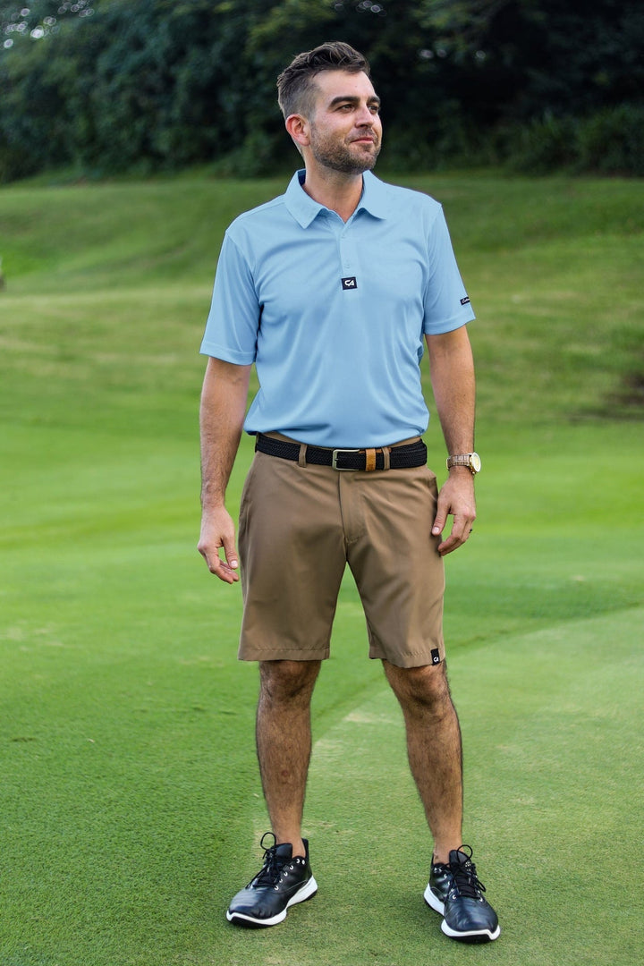Light blue polo shirt with black trim and logo, brown shorts, navy sneakers.