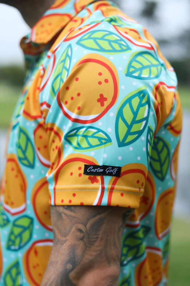 Orange and green citrus-themed golf shirt with a vibrant pattern.