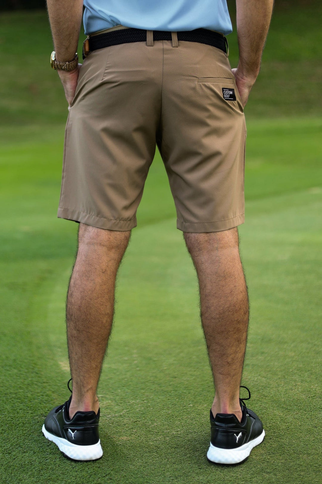 Khaki golf shorts with black belt and white logo on the left leg.