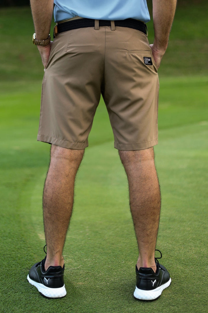 Khaki golf shorts with black belt and white logo on the left leg.