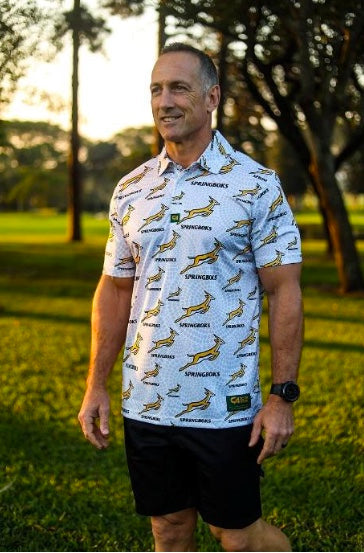 White short-sleeved shirt with green and yellow springbok design, black shorts.