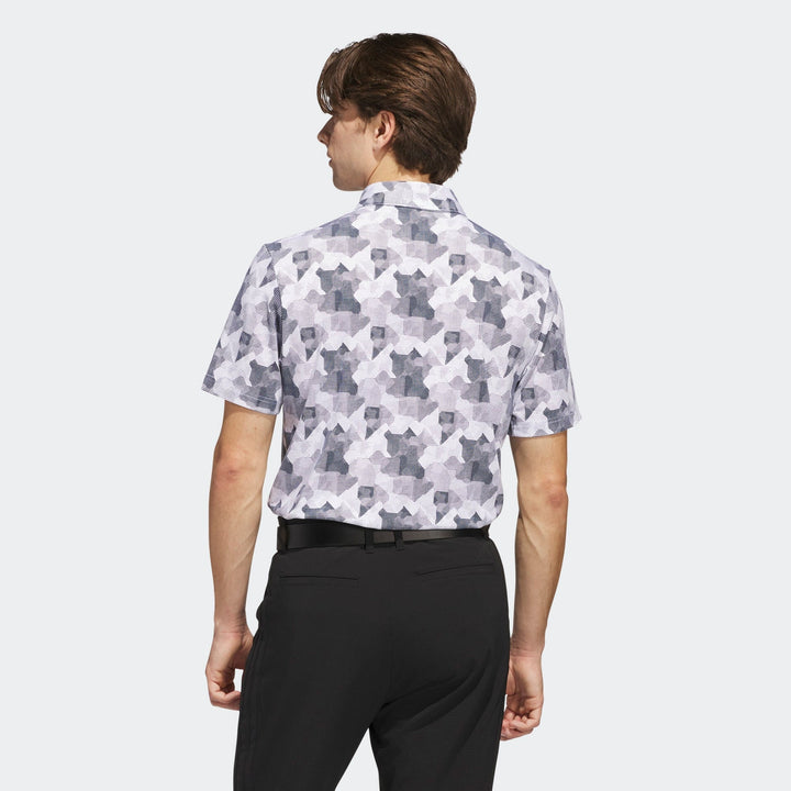 White and black geometric patterned golf shirt with short sleeves, likely made of polyester or cotton blend.