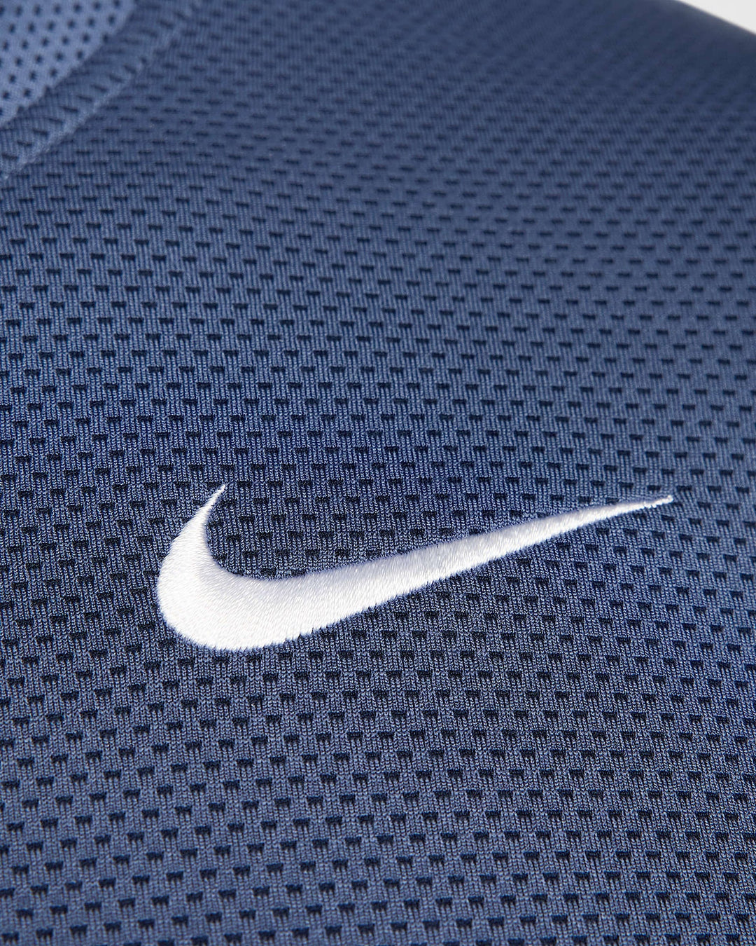 Nike swoosh on navy blue mesh fabric.